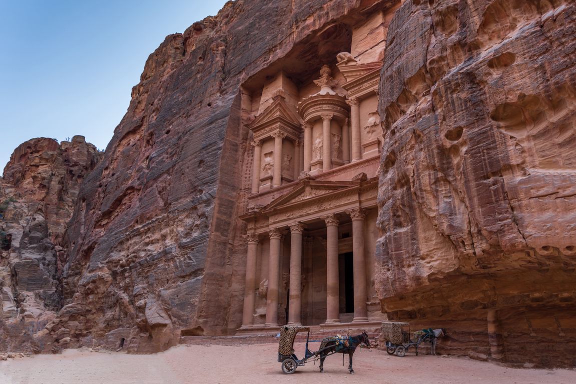 Panoramic view of Petra's Treasury at golden hour with sandstone cliffs glowing amber and rose