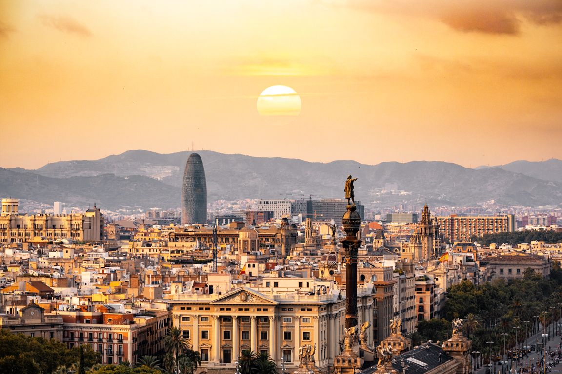 Panoramic view of Barcelona skyline with Sagrada Familia rising above terracotta rooftops at golden hour