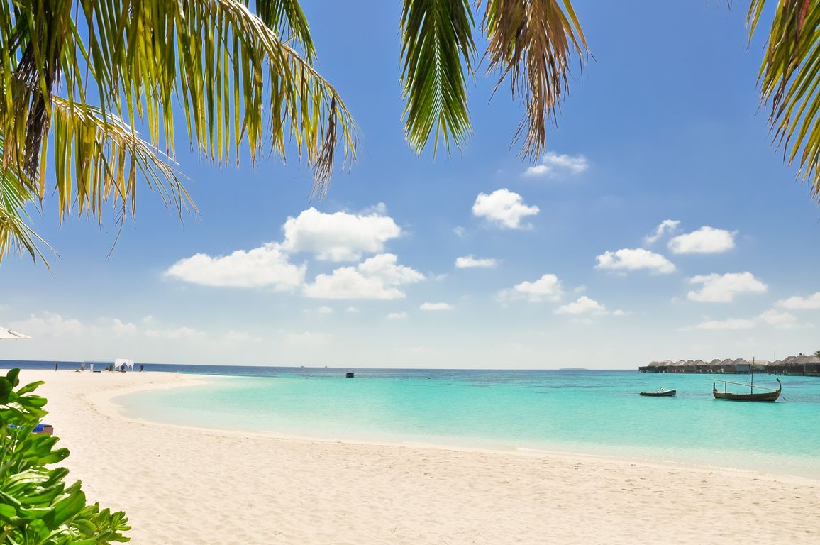 Turquoise water and white sand beach in Nungwi Zanzibar with traditional dhow boats moored offshore